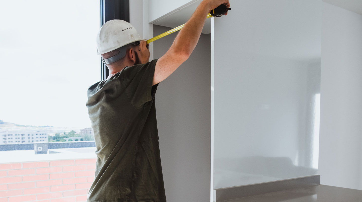 Mains d'installateur vérifiant les dimensions d'encastrement d'un réfrigérateur